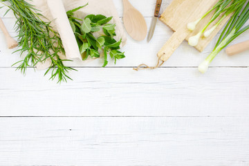 White wooden background with fresh greens and kitchenware