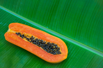 Half of papaya on banana leaf. Tropical summer background
