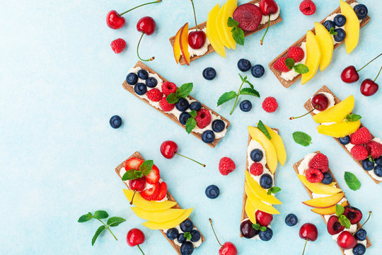 Snack or dessert from sandwiches with creamy cheese and berry fruits top view. Easy summer food for breakfast or lunch.