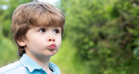 Cute kiss. Child with kiss icon gesture. The little boy made funny lips. Preschooler. Love and family. Surprised child on the background of nature.
