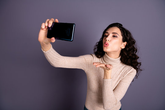 Close up photo attractive she her wavy lady hold hands arms telephone make take selfies send air kiss friends boyfriend speak skype wear casual beige pastel sweater pullover isolated grey background