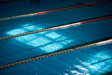 Water surface in the sports swimming pool. Blue water and swim lane dividers. Sports and health concept.