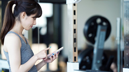 スマホを使う女性　フィットネスジム