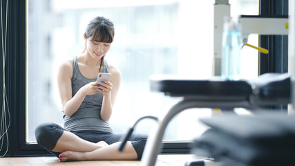スマホを使う女性　フィットネスジム