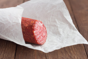 smoked sausage, salami Finnish sliced, wrapped in paper on wooden background