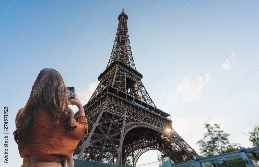 Wall mural travelling in europe, traveler woman taking photo of eiffel tower, famous landmark and travel destin