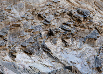 Surface of rocky wall with different hardnesses where the parts of the hardest rock stand out, forming slienties. Can be used as background.