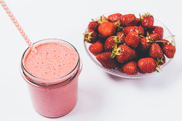 Strawberry smoothie in glass next to bowl