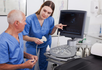 Obraz premium elderly doctor and nurse in cabinet of ultrasound test