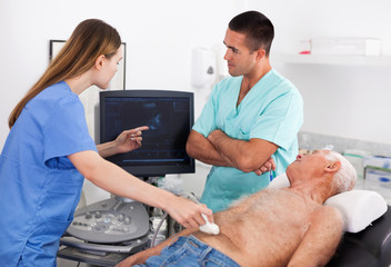 Two confident sonographers working together examining patient with modern ultrasound machine