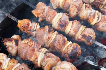 Food on the fire, picnic. Cooking grilled fragrant tasty hot barbecue shashlik on coals on the grill of pickled meat of pork, lamb and beef with onions on skewers