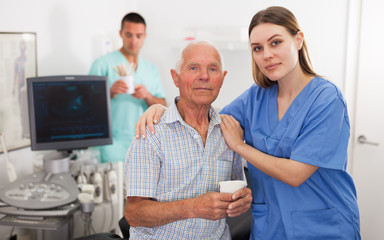 Obraz premium Woman doctor and elderly man patient before ultrasound diagnostic