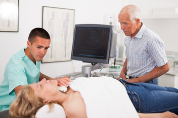 Obraz premium Doctor conducting ultrasound examination of patient's thyroid lying