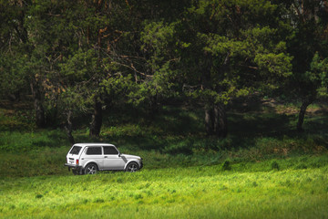 Obraz na płótnie Canvas White car SUV among green hills