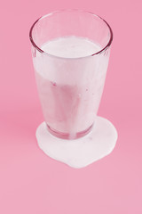 Glass of yogurt on pink background