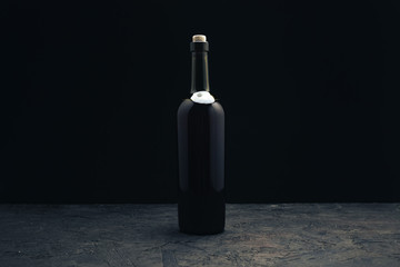 Fototapeta na wymiar Bottle of red wine on a dark wooden table black background behaid.