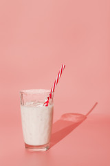 Milkshake in glass on pink background