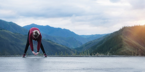 Running stretching. Athlete at the top of the mountain.