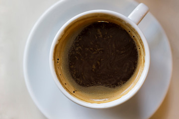 Cup of black coffee on white plate on table. Top view, flat lay, copy space, mock up