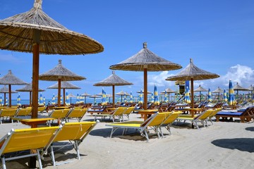 Umbrellas and chaise lounges on the sandy beach. Beach chairs, beds and umbrellas on a tropical beach. Deck chairs and umbrellas on a sandy beach. Summer holiday season concept