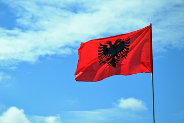 Flag Republic of Albania. Albanian flag on a flagpole waving on a blue sky 