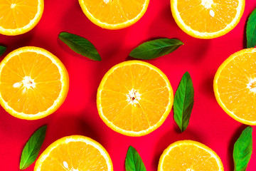 Fototapeta na wymiar Colorful picture of fresh orange slices and mint leaves on a red background. Top view