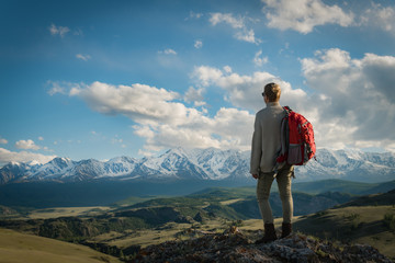 Adult woman hiker stands on the top enjoys mountain views.