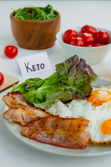Ketogenic diet food. Fried eggs, bacon and lettuce on a plate. Keto diet concept
