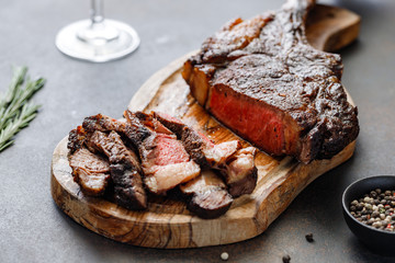Roasted dry-aged marble beef steak Tomahawk on wooden board with spices. Close-up, dinner concept.