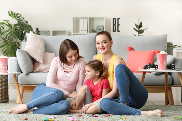 Happy lesbian couple with little daughter at home