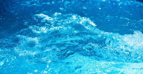 Blue and bright water in swimming pool with sun reflection. Motion of ripple water and  wave in pool, background.