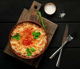 italian pasta spaghetti with tomato sauce, on a plate against the background of dark stone. View from above,