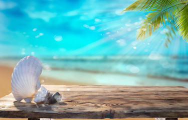 Beautiful seashells on the wooden table against the blue sea and palm trees