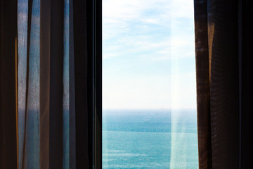 Sea view from the window with curtains. Summer day. 