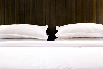 Bed with white pillows in hotel room. 
