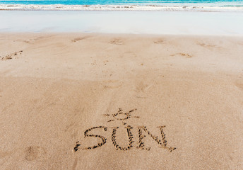 Fototapeta na wymiar Sun (inscription) on the beach (sand) by the sea or ocean. Summer mood concept.