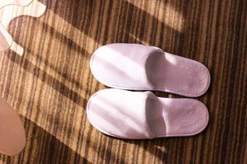 Slippers. White slippers on hotel carpet and sun glares. 