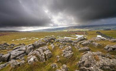 Distant hikers walking towards Pen-y-ghent in the Yorkshire Dales.