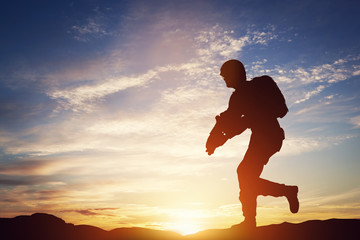 Soldier in combat. Sunset sky, sun shining