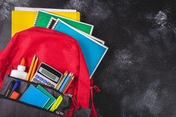 Backpack With School Supplies on a Blackboard Background - 274884353
