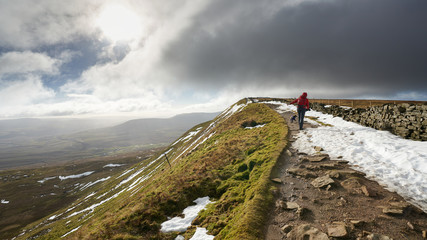 A hiker walking up to the summit of Whernside, part of the Three Peaks in the Yorkshire Dales, England.