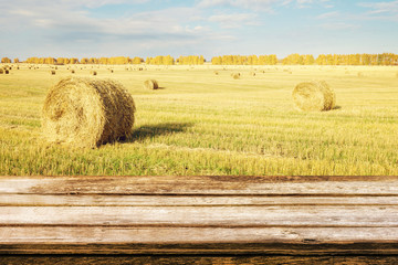 Empty wooden table with autumn landscape of beveled field and straw bales. Mock up for display or montage products