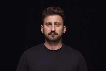 Close up portrait of young caucasian man isolated on black studio background. Photoshot of real...