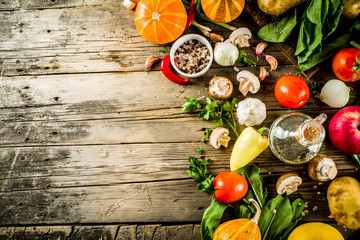 Autumn food concept. Healthy organic harvest vegetables and ingredients pumpkin, greens, tomatoes, corn, wooden kitchen table background. Thanksgiving seasonal cooking ingredients.