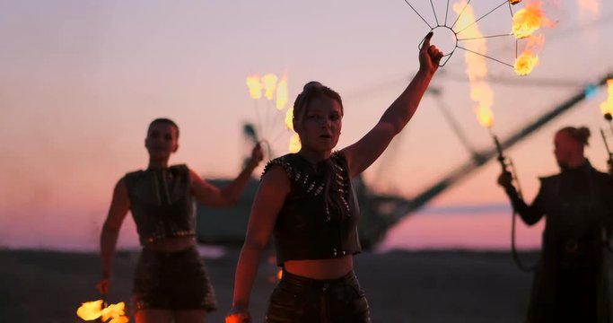 Women with fire at sunset on the sand dance and show tricks against the beautiful sky in slow motion.