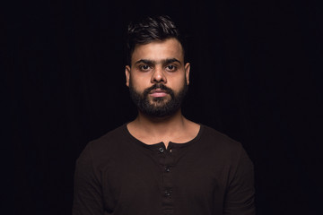 Close up portrait of young hindoo man isolated on black studio background. Photoshot of real...