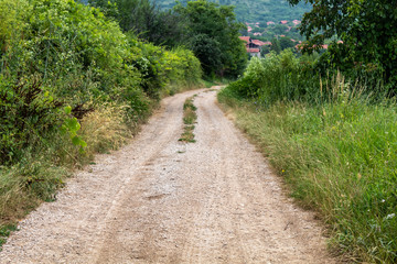 Fototapeta na wymiar Dirt Road With Village in The Background