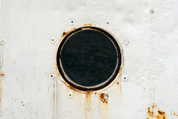 Round window in metallic rusty ship wall