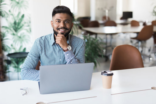 Young indian man smiling and working at modern office