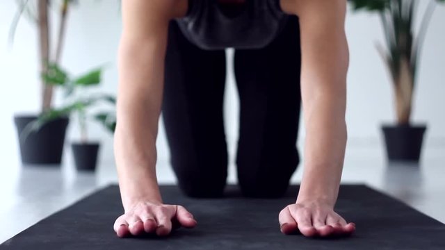 Closeup young woman is doing exercises asanas complex of diamond, downward facing dog, four limbed staff poses. Athletic female in black uniform is practicing yoga. Healthy lifestyle concept.